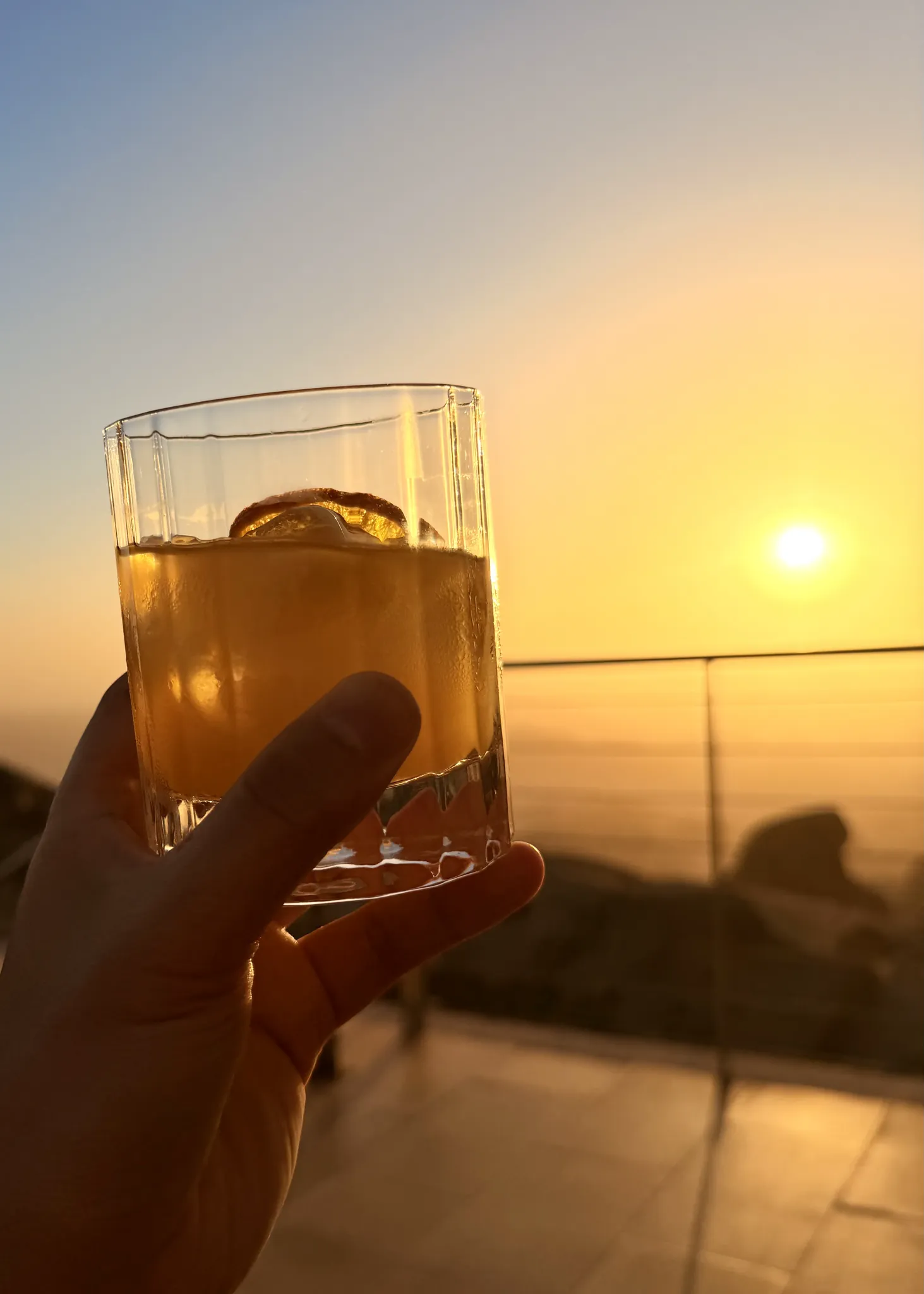 手持鸡尾酒杯对准金色夕阳